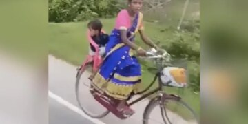 मां का जुगाड़: अपने बच्चे को कुर्सी पर बैठाकर साइकिल चला रही है महिला, लोग कर रहे हैं सलाम