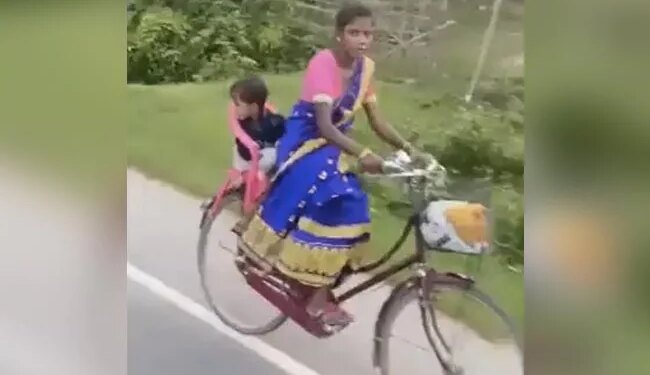 मां का जुगाड़: अपने बच्चे को कुर्सी पर बैठाकर साइकिल चला रही है महिला, लोग कर रहे हैं सलाम