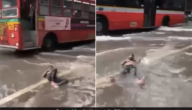 Man Lying Comfortably On A Waterlogged Street Amid Mumbai Rains Internet Says Feeling Maldives In Malad See Viral Video – मुंबई की बारिश में पानी से भरी सड़क पर आराम से लेटकर चिल करते दिखा शख्स, लोग बोले